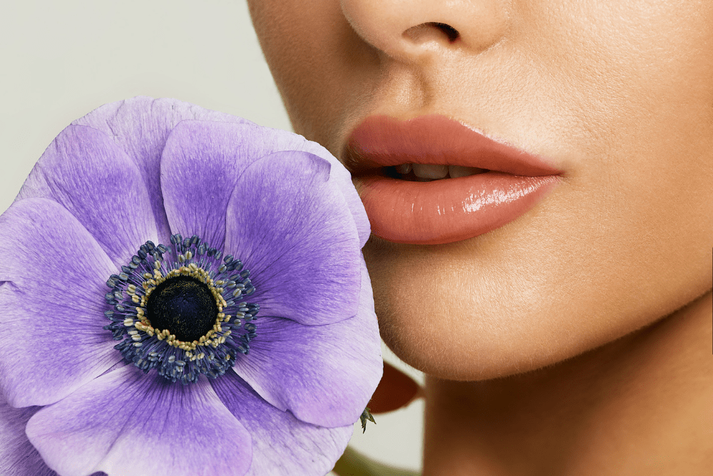 Beautiful lips after augmentation  with lip filler. Sensual female lips with purple flower